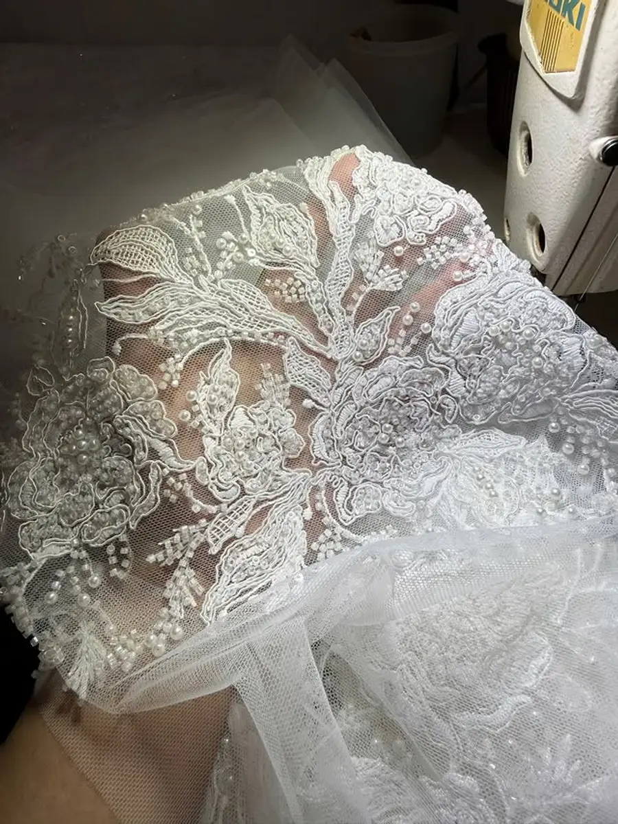 Close-up lace and pearl embroidery used in custom wedding dress pricing and quote review
