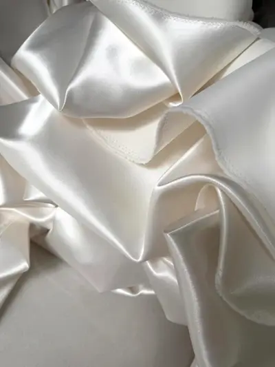 Heavy ivory satin swatch — the yardage Mei Lin approved for her corset split Aline reception look